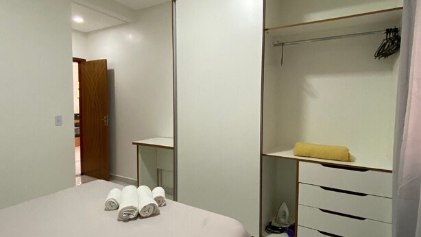 A bedroom with a bed, a wardrobe, and a bathroom. - Condomínio com Piscina á 500m da Praia (Porto Seguro)