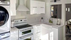 Een moderne keuken met witte kasten, een inbouwoven en een magnetron.