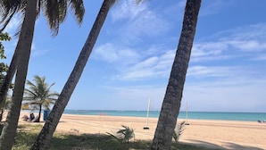 Una playa con palmeras, una red de voleibol y cielo despejado.