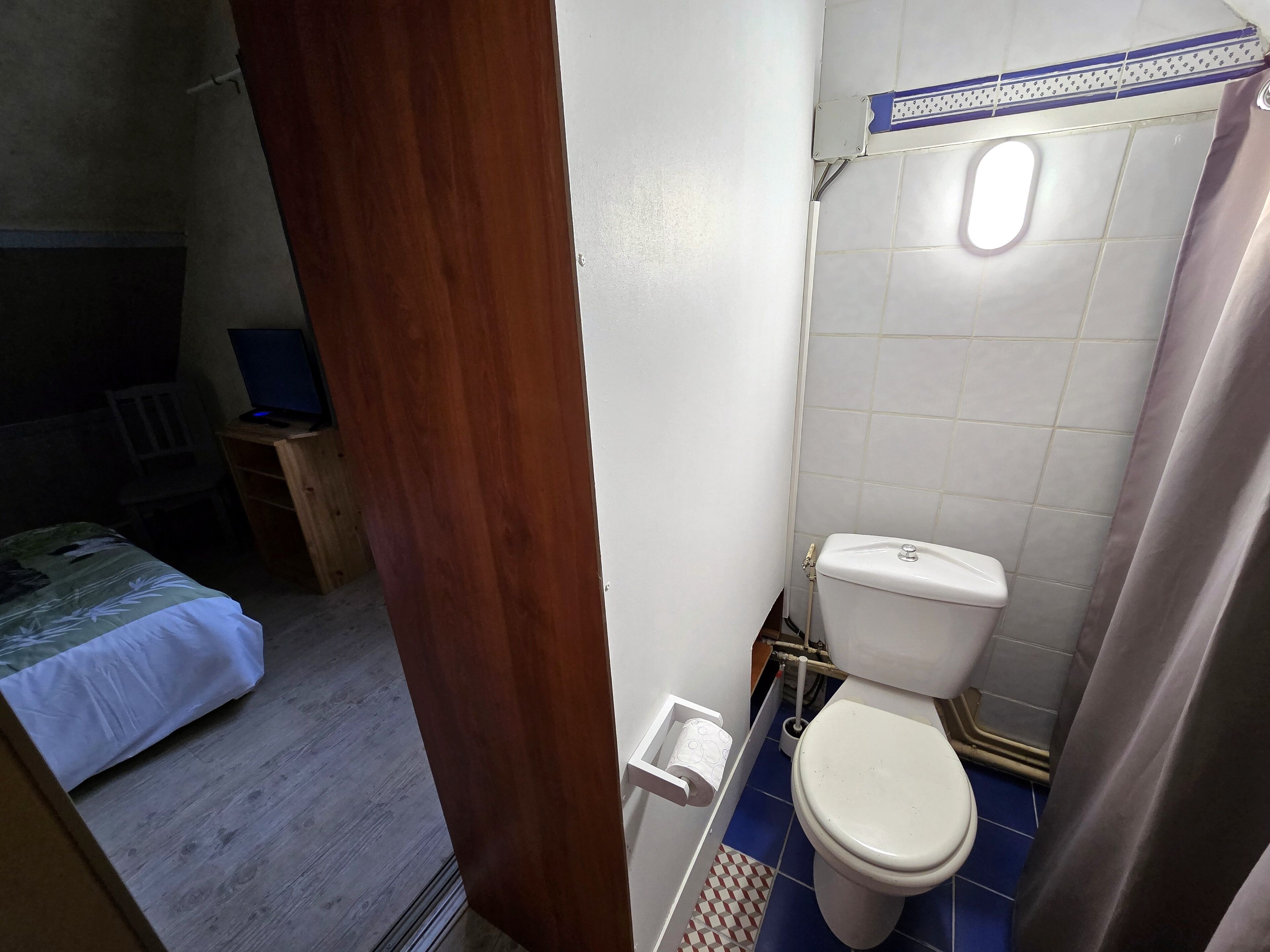 A small, compact bathroom with a toilet, a shower curtain, and a sink.