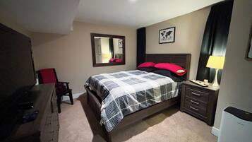 A bedroom with a bed, a desk, a chair, a dresser, a lamp, and a framed picture on the wall.
