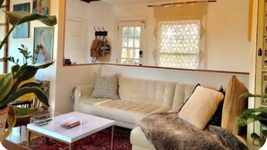 A cozy living room with a sofa, a coffee table, and string lights. - Close-in Private Getaway in the trees of Portland (Portland)