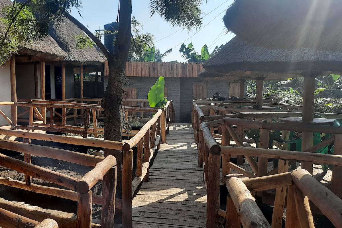 Une terrasse en bois mène à un bâtiment au toit de chaume, doté de nombreuses fenêtres et portes.