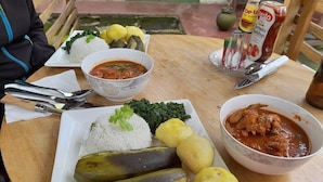 A table with a plate of rice, vegetables, and two bowls of soup. - Sunscape lodge  (Fort Portal)