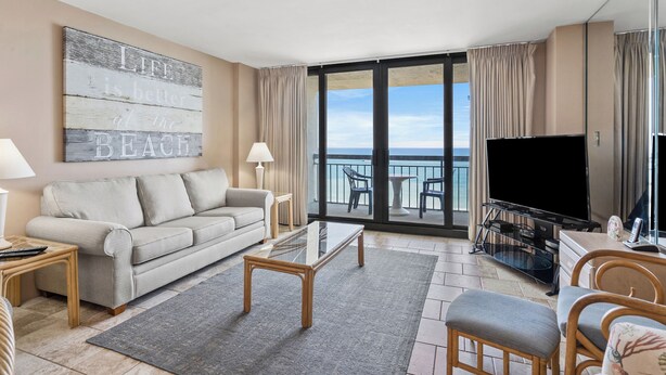 Hotelkamer met balkon, een bank, salontafel, televisie en een eethoek.