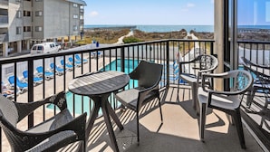 A balcony with a pool, lounge chairs, and a view of the beach and ocean. - Sedgefield 102 (North Myrtle Beach)