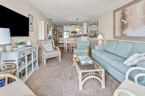 A living room with a sofa, chairs, a coffee table, and a TV. - Sea Cloisters 302b (North Myrtle Beach)