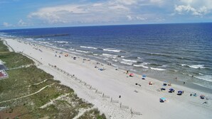 A beach with a wooden walkway and a pier extending into the ocean. - Sunrise Pointe 11F (North Myrtle Beach)