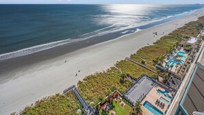 A beach resort with a long sandy beach, a pool area, and a view of the ocean. - Ashworth 1809 (North Myrtle Beach)