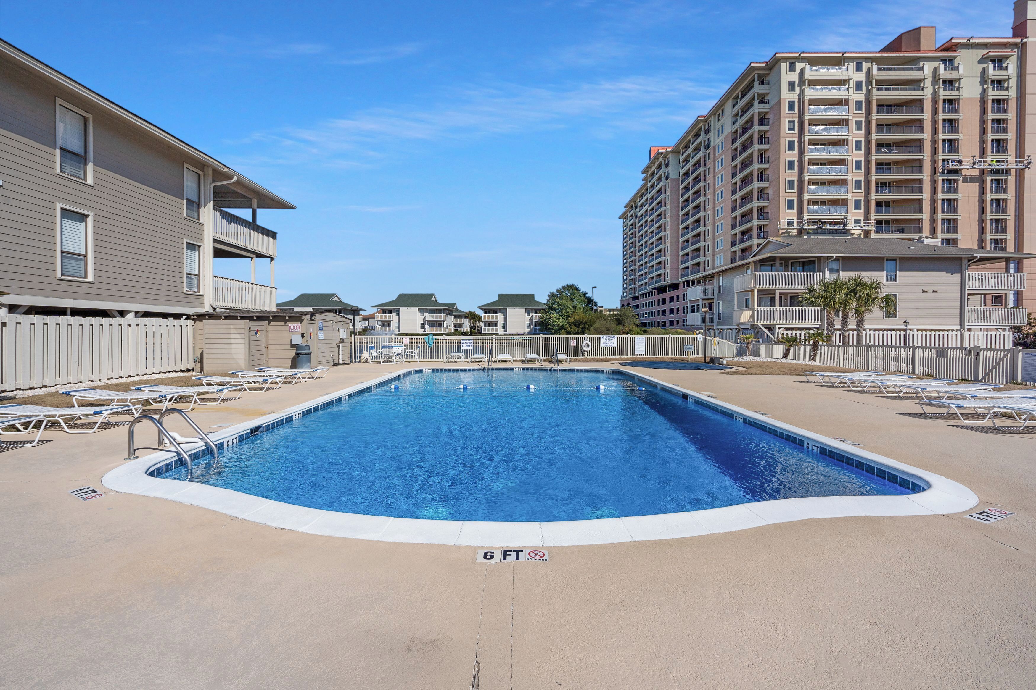 A swimming pool with lounge chairs, a 6 FT depth marker, and a white picket fence.