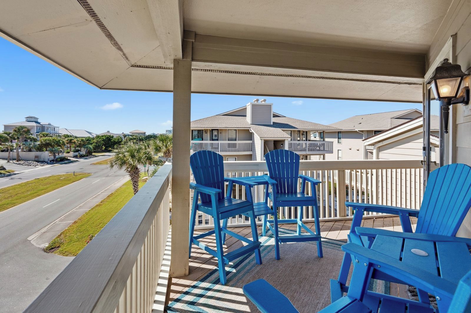 A balcony with blue chairs and a view of a street and buildings.