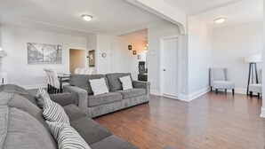A spacious living room with a grey sectional sofa, a grey armchair, and a small table with chairs.
