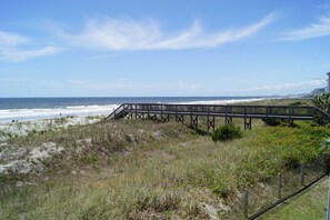 A wooden boardwalk leading to a beach with a clear view of the ocean and distant city skyline. - Sea Cloisters 204d (North Myrtle Beach)