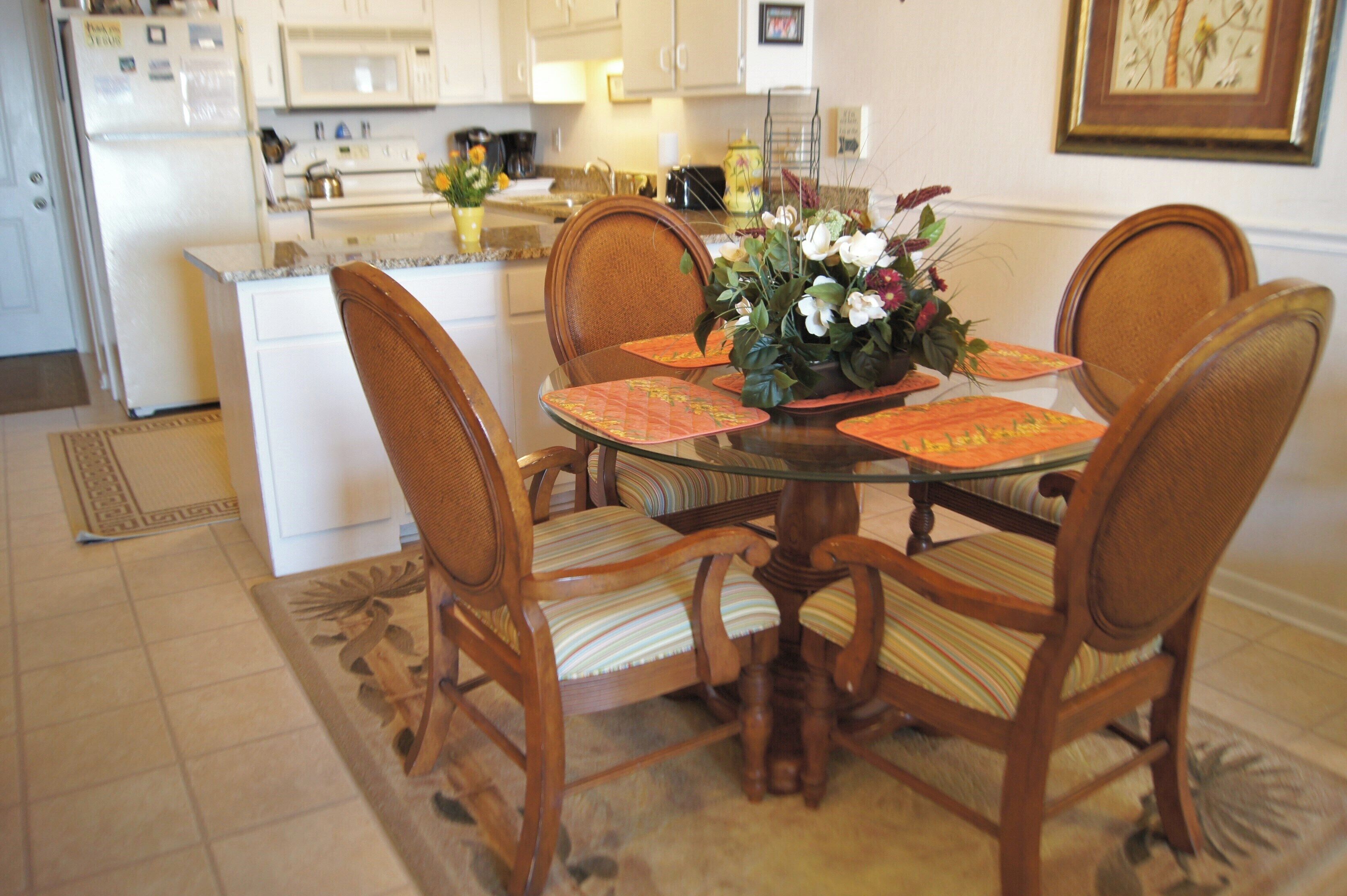 Un'area pranzo con un tavolo in vetro, sedie in legno e un vaso di fiori.