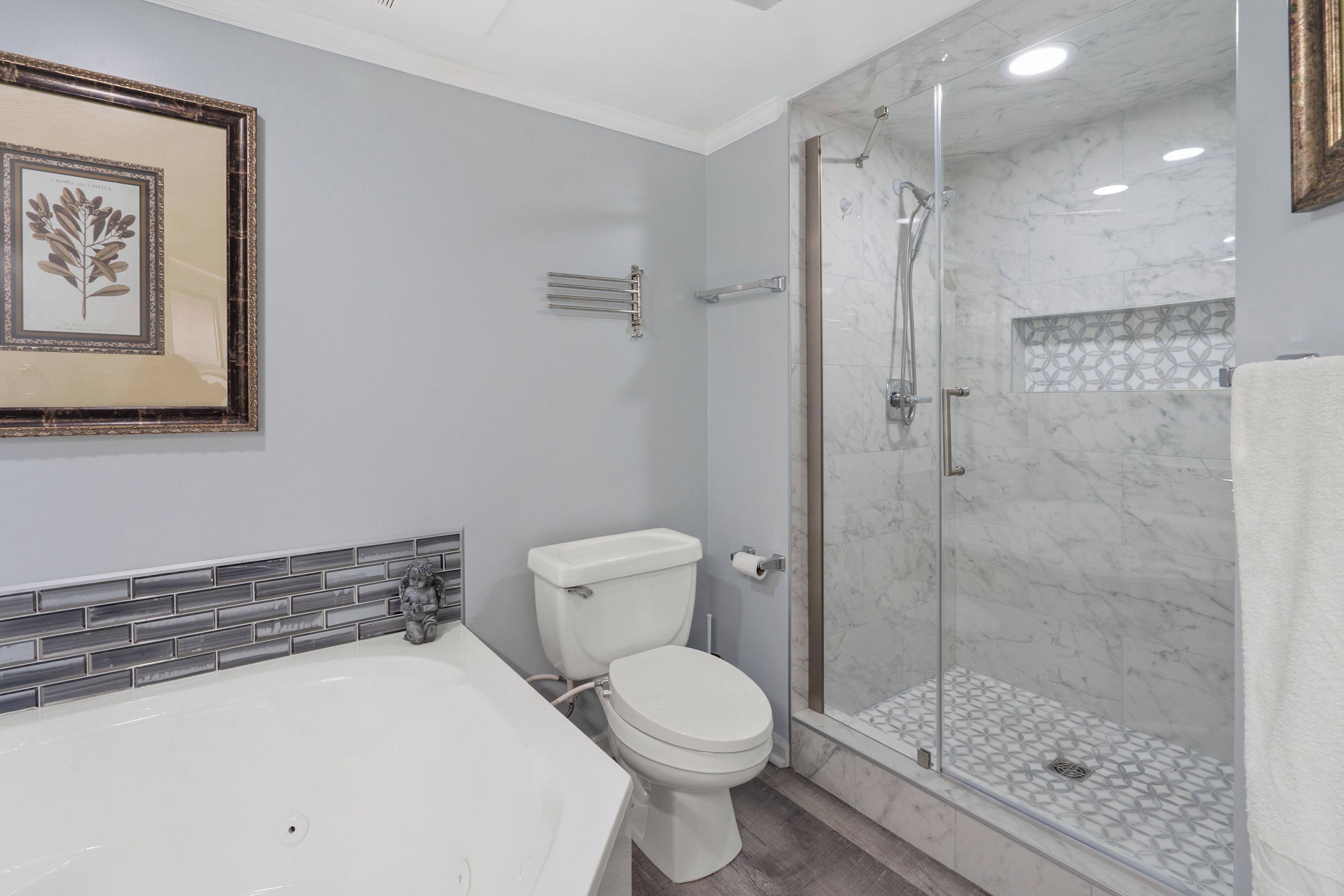A modern bathroom with a bathtub, toilet, and glass-enclosed shower.