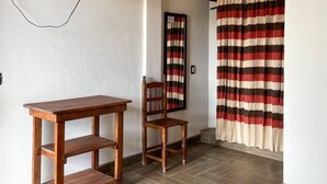 A room with a ceiling fan, a TV mounted on the wall, a wooden table, a chair, and a striped curtain. - Hotel Yubazuu Mitla (San Pablo Villa de Mitla)