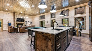 A spacious living area with a pool table, comfortable seating, and a fireplace.