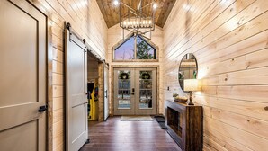 A wooden interior with a central door, a fireplace, and a chandelier.