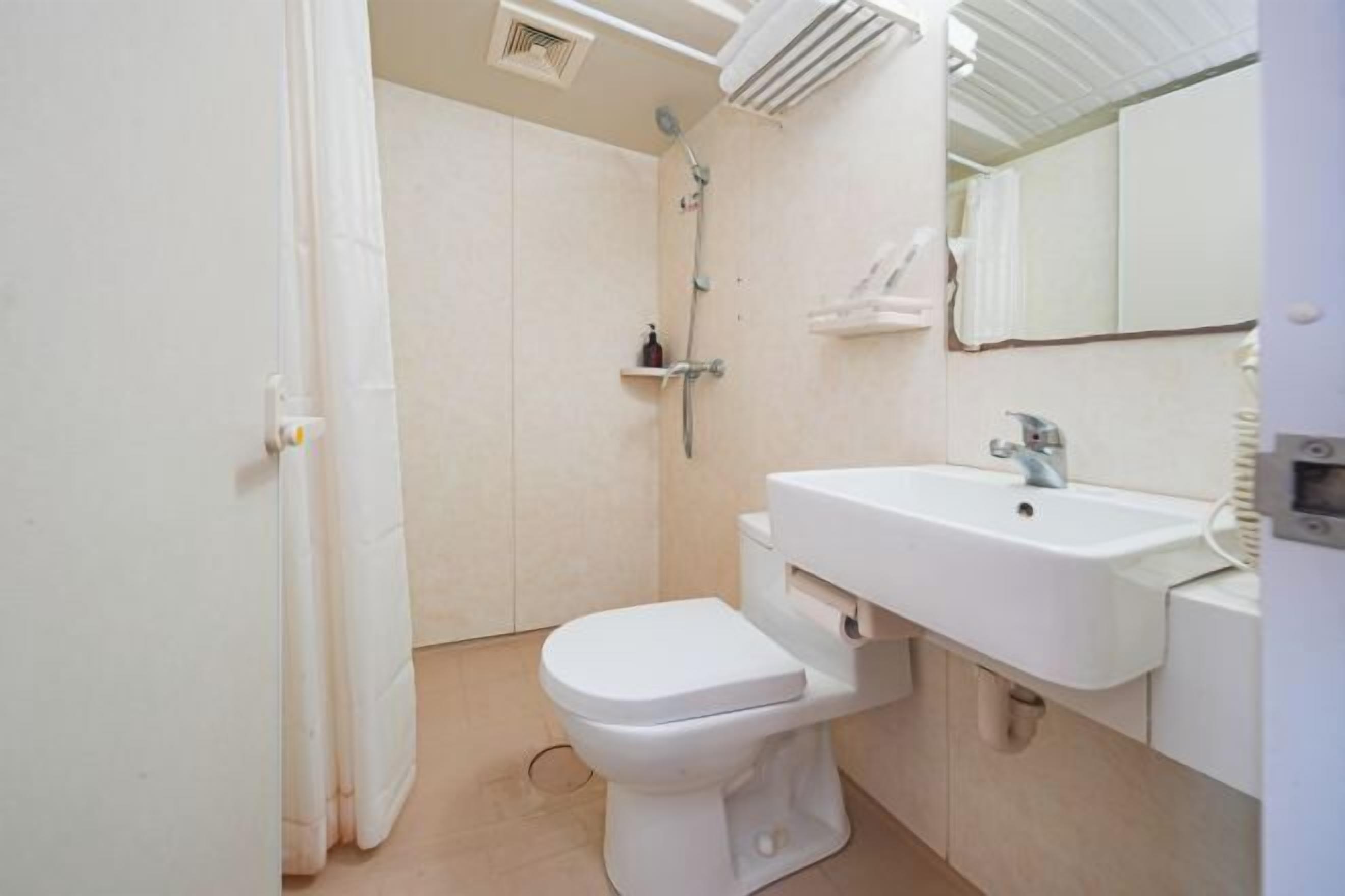 A small, clean bathroom with a toilet, sink, and shower.