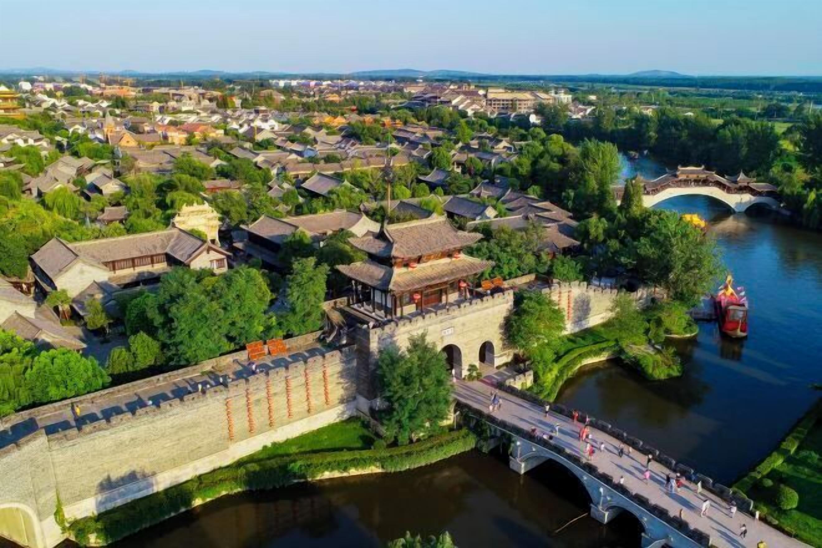 A traditional town with a river, a bridge, and a stone wall.
