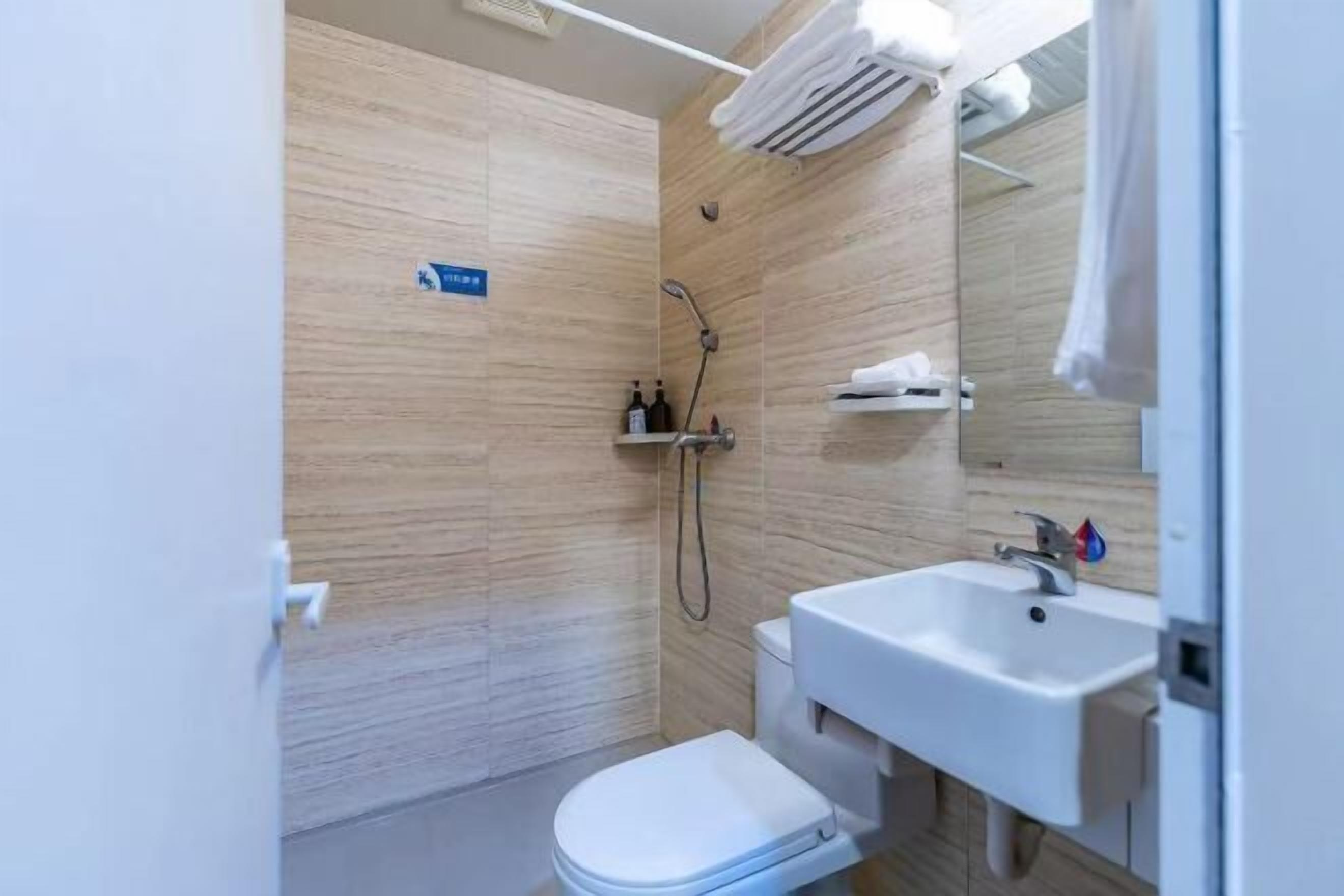 A compact bathroom with a toilet, sink, and shower.