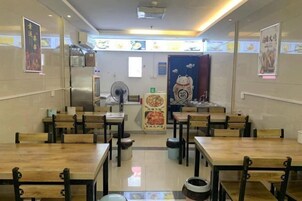 A restaurant interior with wooden tables and chairs, a central counter, and posters on the walls.