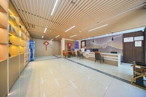A modern reception area with a wooden ceiling, a reception desk, several chairs, and a tiled floor.