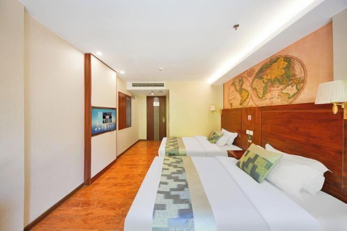 A hotel room with two beds, a wooden headboard, a map on the wall, and a television on the left side.