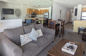 Una sala de estar moderna con un sofá gris, una mesa de centro de madera y un televisor.