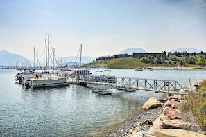 Un puerto deportivo con barcos amarrados, un muelle de madera y una costa rocosa.