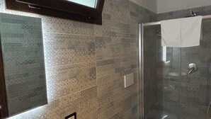 A bathroom with a large mirror, a sink, a toilet, and a shower area.