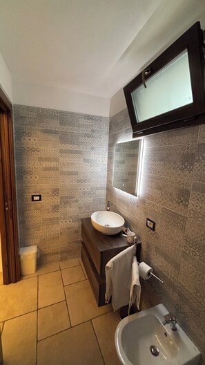 A bathroom with patterned tiles, a round sink, a rectangular sink, a mirror, and a toilet. - Camera Il Vico – Charming Historic Room with Kitchenette, Sleeps 4 (Pulsano)