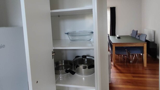 Une cuisine avec des meubles blancs, une table à manger avec des chaises et un plancher en bois.