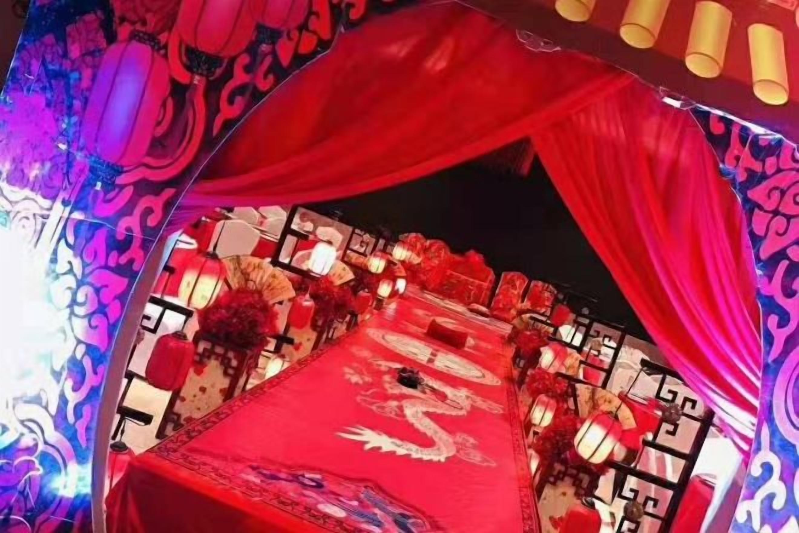 A banquet hall with a red tablecloth, floral centerpieces, and traditional Chinese lanterns.