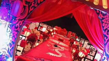 A banquet hall with a red tablecloth, floral centerpieces, and traditional Chinese lanterns.
