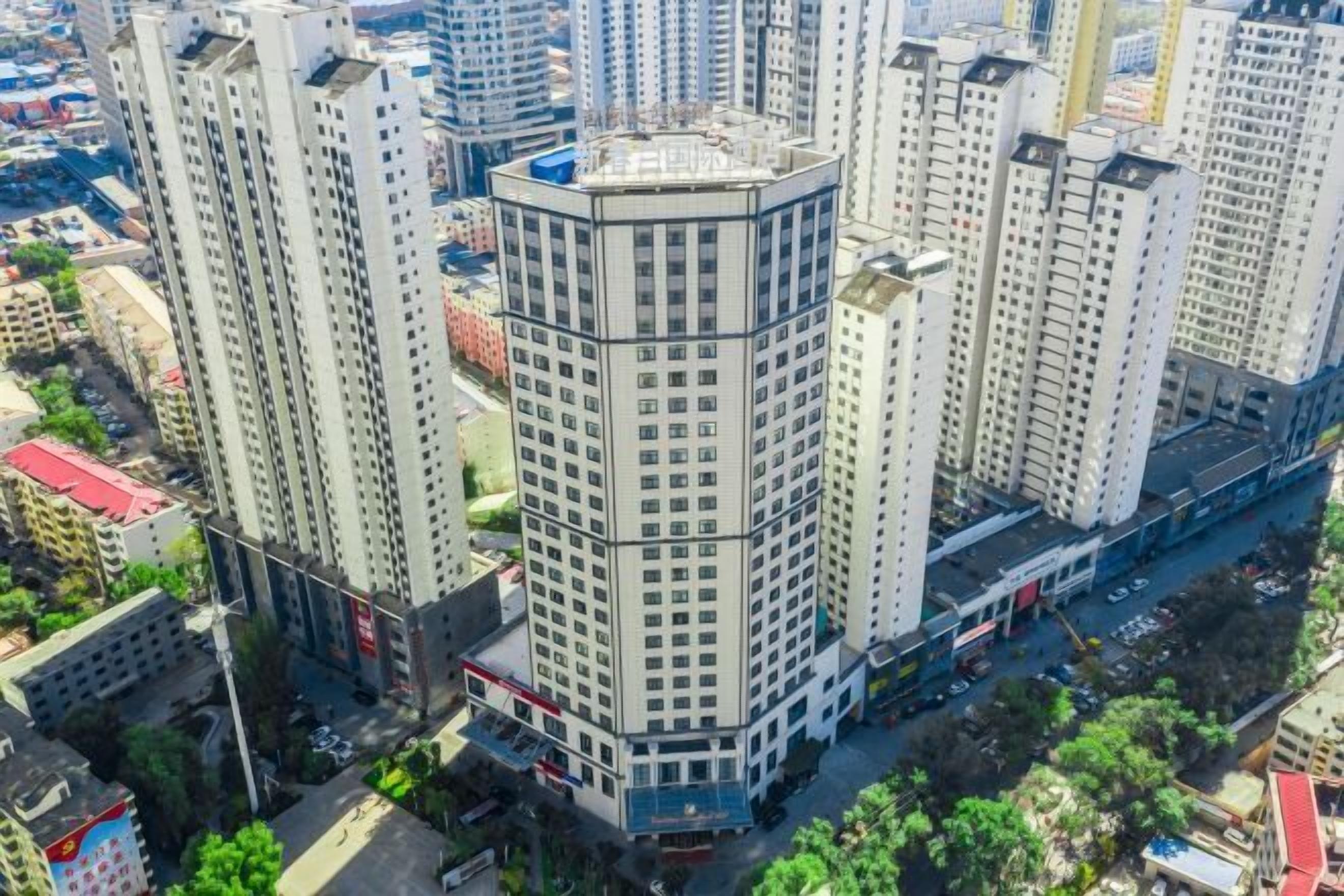 A high-rise building with a corner design, surrounded by other tall buildings.