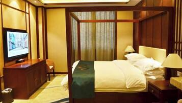 A hotel room with a bed, television, and a desk with a lamp.