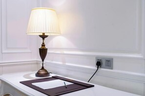 A table with a lamp, a notepad, and a pen.