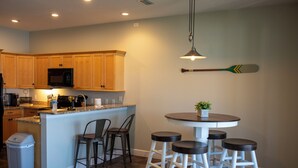 A kitchen with wooden cabinets, a microwave, a coffee maker, and a bar area with stools. - Lakefront Retreat with Pool (Lake Placid)