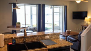 A kitchen with granite countertops, a sink, a dining area with a table and chairs, and a large window with curtains. - Lakefront Retreat with Pool (Lake Placid)