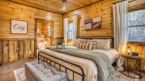 Un dormitorio de cabaña de madera acogedor, con cama, banco, mesita de noche y vistas al exterior.