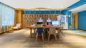 A modern hotel lobby with a wooden reception desk, two chairs, a laptop, and a vending machine. - Xuefu Hotel (Shenzhen Science Park Nanshan Subway Station Branch) (Shenzhen)