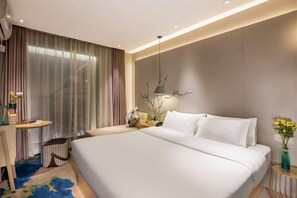 A modern hotel room with a large bed, a desk, a chair, a small table, and a decorative plant. - Xuefu Hotel (Shenzhen Science Park Nanshan Subway Station Branch) (Shenzhen)