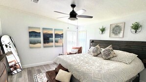 A bedroom with a large bed, a ceiling fan, a bench, and a rug.