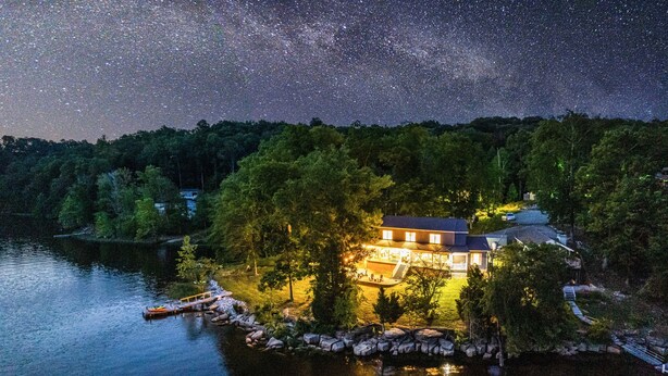 A lakeside house with a dock, surrounded by trees and a clear night sky. - Lakefront | Dock, 4 Kayaks, Firepit, Sleeps 8 (Lewisburg)
