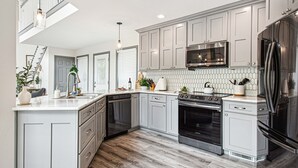 A modern kitchen with grey cabinets, stainless steel appliances, and a wooden floor. - Lakefront | Dock, 4 Kayaks, Firepit, Sleeps 8 (Lewisburg)