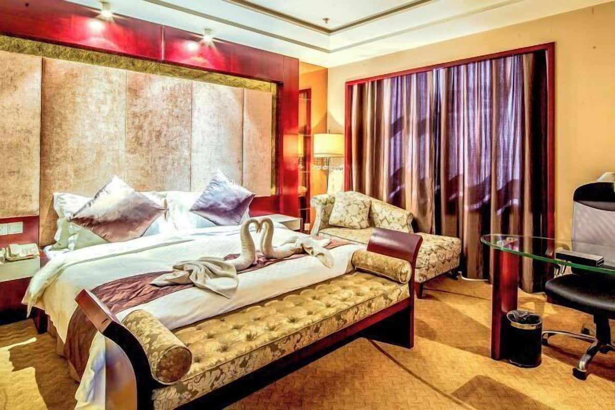 Ein Hotelzimmer mit einem großen Bett, einer Couch, einem Schreibtisch und einem Stuhl.