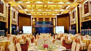 A banquet hall with round tables, white chairs, and a stage with a screen. - Fengyan Jianguo Hotel (Pingyao Ancient City) (Pingyao)