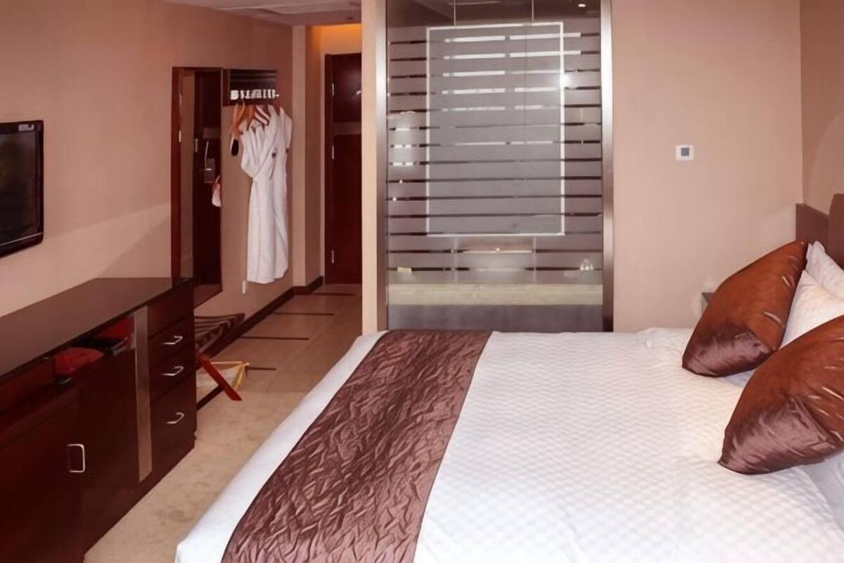 Ein Hotelzimmer mit Bett, Fernseher, Kleiderschrank und Spiegel.