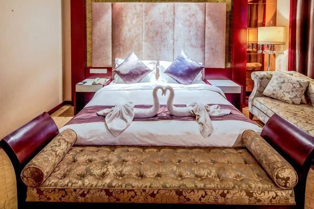 Ein Hotelzimmer mit einem großen Bett, einer Couch, einem Nachttisch und einer Lampe.